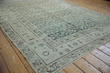 Angled view of a vintage Hamadan carpet's serpent-style border and low-pile texture.