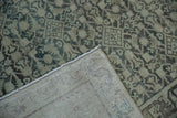 Corner of a distressed Hamadan rug folded back to reveal its hand-knotted foundation.