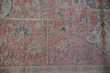 Distressed pile texture of vintage Sparta carpet, showing faded pink, blue, and beige floral vinery.