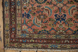 Vintage Hamadan rug corner with dusty blush Herati pattern, navy and celadon accents, and cream fringe.