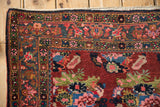Corner of vintage Bijar rug showcasing dark cherry field, ornate borders, and original selvage.