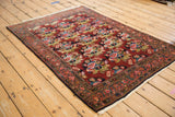 Vintage Bijar rug with rose bouquets in blue, green, and pink on a deep red field.