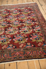 Vintage Persian Bijar rug close-up showing rose bouquets in cherry red, sky blue, and green.