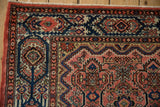 Vintage Malayer rug, upper corner showing dusty rose floral field, navy cartouche border.