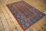 Angled view of the traditional Persian Malayer rug's navy border and dusty rose floral field.