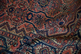 Textured hand-knotted pile with navy cartouche border and dusty rose floral motifs.
