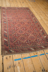 Geometric style Belouch rug corner with distressed raspberry burgundy guls and dark teal patterns.