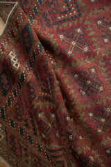 Distressed Belouch runner detail with raspberry burgundy serrated guls and dusty teal geometric motifs.