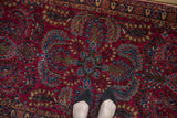 Detail of the central medallion's blue and bronze floral sprays on a cherry red Sarouk rug.