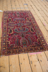 Angled view of a vintage Sarouk runner displaying its floral bouquets across a cherry red field.
