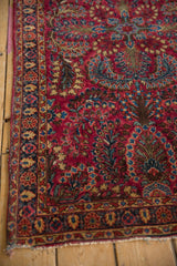 Detailed floral border and sprays on the cherry red field of a vintage hand-knotted Sarouk rug.