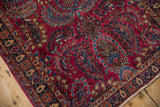 Classic Sarouk floral sprays in dusty bronze and blue on the rich cherry red field of the rug.