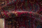 Soft, cherry red pile of a vintage Sarouk rug showing detailed floral sprays in blue and dusty bronze.