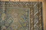 Storied wear on antique Caucasian rug's geometric guls and wave border in blue, olive, and sand.