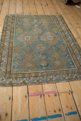 Distressed antique Caucasian rug corner with blue, sand, olive geometric guls, wave border, fringe.