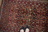 Corner detail of a vintage Belouch rug with serrated geometric borders and pomegranate motifs.