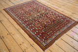Angled view of a vintage Belouch rug's pomegranate garden pattern and intricate geometric borders.