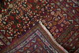 Folded corner of a vintage Belouch rug showing the intricate geometric border and hand-knotted back.