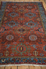 Brick red vintage Mehreban rug with geometric trident medallions and meandering vine border.