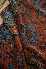 Vibrant brick red and sky blue trident and ram's horn motifs on vintage Mehreban rug fold.