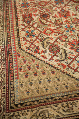 Worn pile on the vintage rug's corner showing the boteh motif spandrel and vine border.