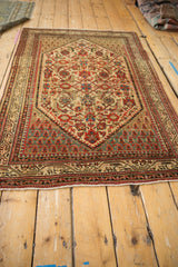 Angled view of a vintage Serbend rug showcasing its traditional Herati design and distressed character.