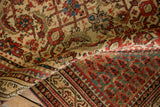 Folded corner of a distressed Serbend rug showing the low hand-knotted pile and intricate Herati motif.