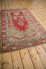 Cherry red and olive green Oushak rug corner, showing even pile wear and intact selvage.