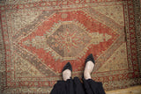 Distressed vintage Oushak rug with hexagonal starburst medallion, dusty red, beige, and ivory tones.