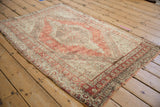 Distressed vintage Oushak rug corner, revealing dusty red, ivory abrash, and worn texture.