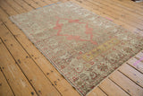 A distressed Kayseri rug shown at an angle, featuring a soft blush medallion and sand-colored field.