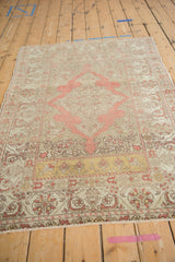A vintage distressed Kayseri rug shown at an angle, highlighting its soft blush and saffron palette.