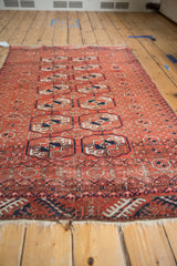 Angled view along a vintage Belouch rug, showing the tattered fringe and geometric motifs.