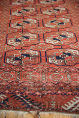 Angled perspective on a vintage Belouch rug showing the low, worn pile and geometric Turkmen guls.
