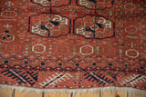 Close-up of the vintage Belouch rug's end border with geometric pawn motifs and ivory fringe.