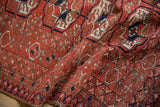 The pliable handle of a vintage Belouch rug, showing its low-pile texture and geometric guls.