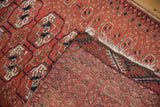 Vintage Belouch rug corner folded over, revealing the hand-knotted back and red geometric pile.