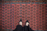 Feet on a vintage Kurdish Hamadan rug featuring blush field and staggered boteh pattern.