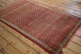 Repeating blossom floral motifs and vinery lattice on the Oushak rug's abrashed cherry red field.