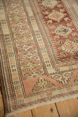 Subtle wear and rose-toned dragon border of a distressed vintage Melas rug.