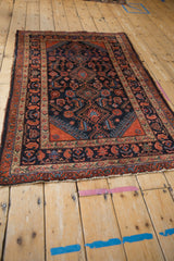 Vintage Malayer rug corner with worn ends, brick red border, and navy Herati field.
