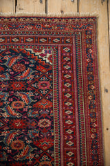 Vintage Turkmen runner corner, showing navy Herati pattern, cherry red geometric borders, and fringe.