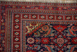 Intricate multi-layered geometric borders of a vintage Turkmen rug in red, navy, and teal.