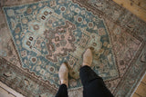 Worn vintage Hamadan rug with a dusty mauve bat-like medallion and teal Herati patterns.