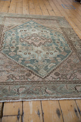 Close-up of distressed Hamadan rug showing wear, visible foundation, and floral vine border.