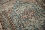 Distressed vintage Hamadan rug detail showing worn teal, mauve geometric patterns and visible foundation.