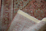 Vintage rug corner with distressed red and blue-green pile, hand-knotted foundation.