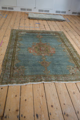 Decorative distressed Malayer rug corner with abrashed blue field, pale raspberry border, and fringe.