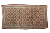 Vintage distressed Belouch rug with an allover geometric lattice pattern in shades of copper, red, and ivory.