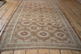 Angled view of a vintage distressed Belouch rug highlighting its allover geometric pattern in copper and ivory tones.